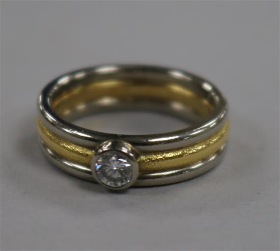 A modern two colour 18ct gold and collet set solitaire diamond ring, size N.